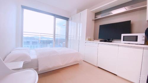 a white bedroom with a bed and a tv at Shine Hotel in Incheon