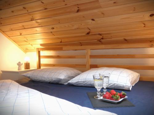 a bed with two pillows and a tray with a plate of fruit at Domki Trzy - 3 in Smołdziński Las