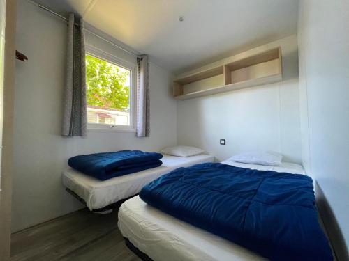 2 Betten in einem kleinen Zimmer mit Fenster in der Unterkunft International Camping Ardèche in Salavas