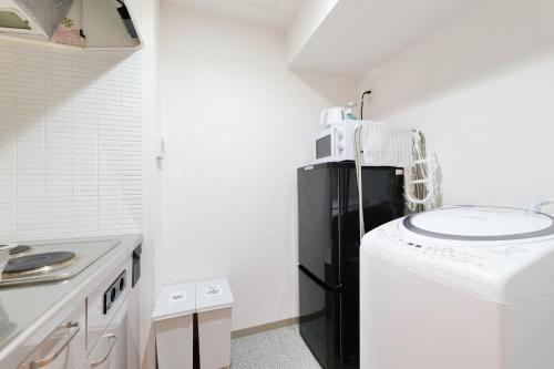 a small kitchen with a black refrigerator and a washing machine at Nakajima Park stay AMS tower 32F Panoramic view of Sapporo city in Sapporo