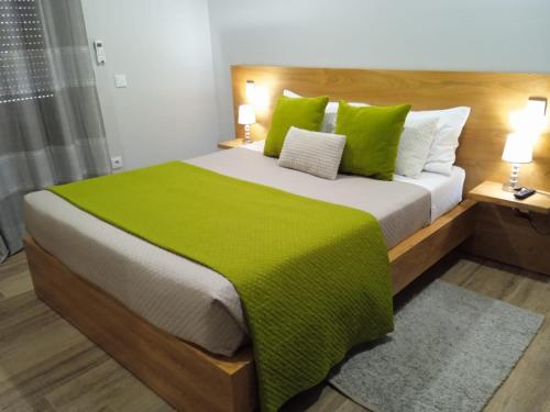 a bedroom with a large bed with green sheets and pillows at Casa do Toucedo - Encanto da Natureza Caniçada / Gerês in Caniçada