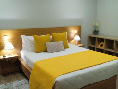 a bedroom with a large bed with yellow sheets and pillows at Casa do Toucedo - Encanto da Natureza Caniçada / Gerês in Caniçada