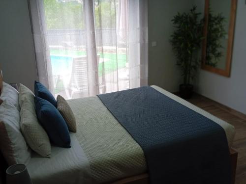 a bedroom with a bed with blue pillows and a window at Casa do Toucedo - Encanto da Natureza Caniçada / Gerês in Caniçada