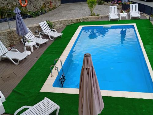 a swimming pool with chairs and an umbrella at Casa do Toucedo - Encanto da Natureza Caniçada / Gerês in Caniçada