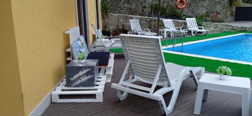 a group of chairs sitting on a deck next to a pool at Casa do Toucedo - Encanto da Natureza Caniçada / Gerês in Caniçada