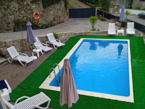 a swimming pool with lawn chairs and umbrellas at Casa do Toucedo - Encanto da Natureza Caniçada / Gerês in Caniçada