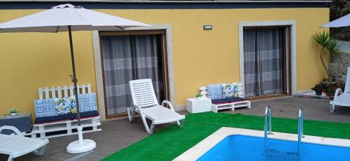 a patio with a pool and chairs and an umbrella at Casa do Toucedo - Encanto da Natureza Caniçada / Gerês in Caniçada