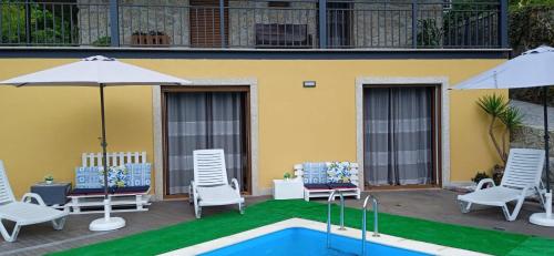 a pool with chairs and umbrellas next to a building at Casa do Toucedo - Encanto da Natureza Caniçada / Gerês in Caniçada