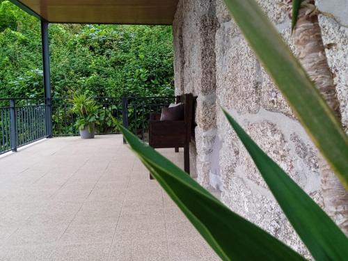 a stone wall with a chair on a patio at Casa do Toucedo - Encanto da Natureza Caniçada / Gerês in Caniçada