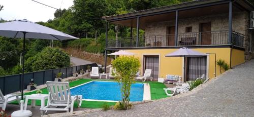 a house with a swimming pool with chairs and umbrellas at Casa do Toucedo - Encanto da Natureza Caniçada / Gerês in Caniçada
