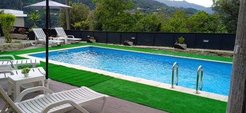 a swimming pool with green grass and white chairs at Casa do Toucedo - Encanto da Natureza Caniçada / Gerês in Caniçada