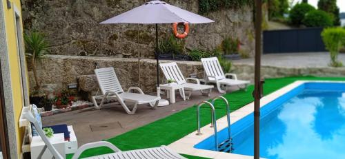 a group of chairs and an umbrella next to a swimming pool at Casa do Toucedo - Encanto da Natureza Caniçada / Gerês in Caniçada