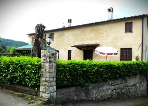 ein Gebäude mit einem Regenschirm und einer Hecke in der Unterkunft La Cheta in Monsagrati