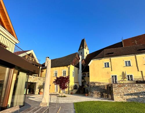 a group of buildings with a clock tower in the background at Weingut FJ Gritsch Mauritiushof Apartments in Spitz