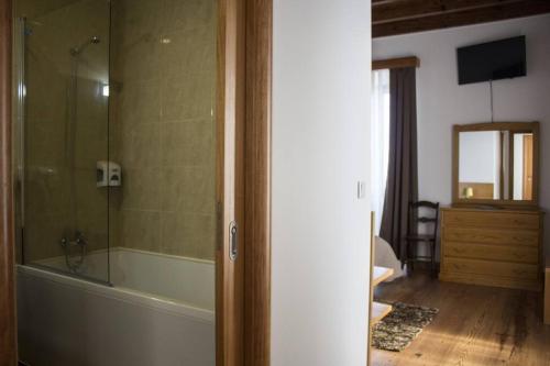 a bathroom with a tub and a glass shower at Casa Lagar de Pedra T3 in Santa Cruz da Graciosa