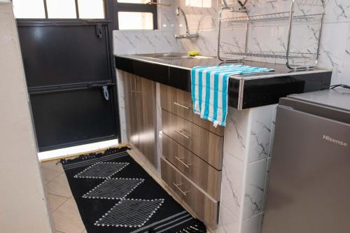 a small kitchen with a sink and a dishwasher at Lux Suites Lumumba Drive Apartments in Nairobi