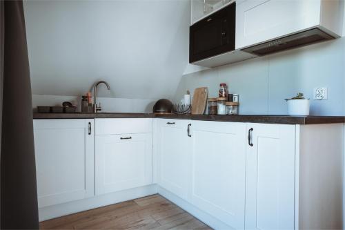 a white kitchen with white cabinets and a sink at Apartamenty Widok Tatr in Zakopane