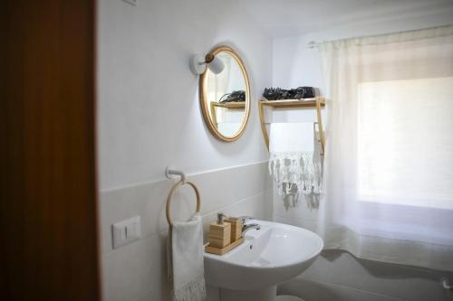 ein weißes Badezimmer mit Waschbecken und Spiegel in der Unterkunft Villa D'Anna in Cefalú