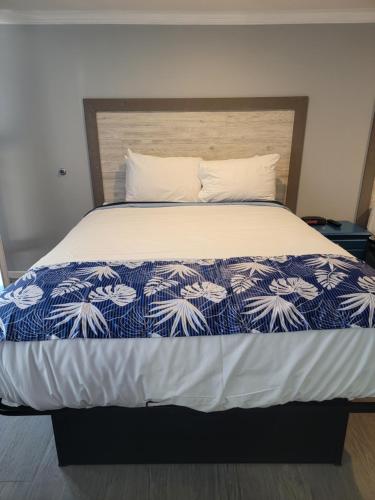 a bedroom with a bed with a blue and white comforter at Tides Motel - Hampton Beach in Hampton