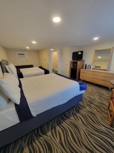 a hotel room with a large bed and a television at Tides Motel - Hampton Beach in Hampton
