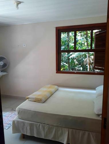 a bed in a room with a window at Casa da Floresta in Paraty