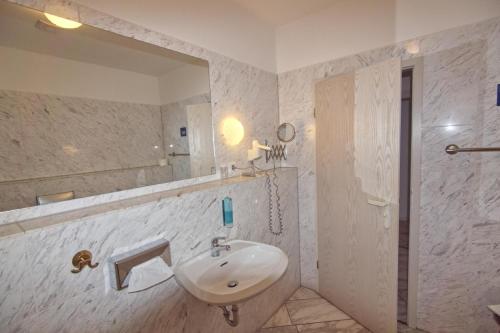 a white bathroom with a sink and a mirror at Hotel Sächsischer Hof in Scheibenberg