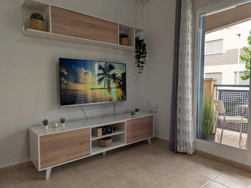 a living room with a flat screen tv on a wall at Apartamento Las Palmeras - Con Terraza, barbacoa, aire acondicionado y a 250m de la playa! in Los Alcázares