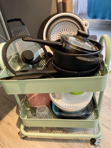 a pile of dishes and utensils sitting on a shelf at AUX 4 LOGIS Appart-hotel - Studio Le Flore - Petit déjeuner inclus 1ère nuit in Foix