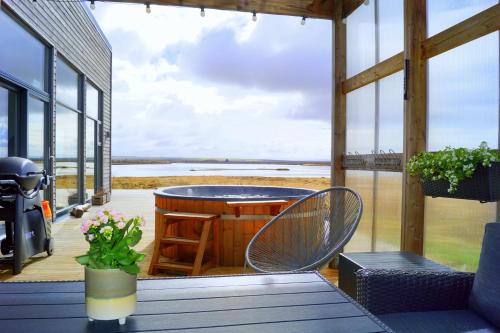 a porch with a table and chairs and a view of the ocean at Austurey - Lakefront Villa in Laugarvatn