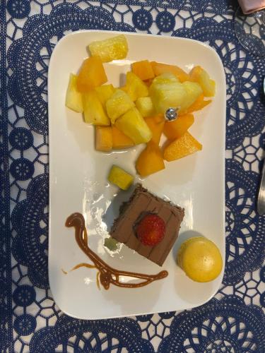 a plate of food with a piece of cake and fruit at Esprit Etape in Saint-Barthélemy-de-Vals