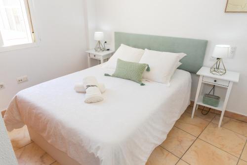 a bedroom with a large white bed with two tables at apartamento playa chica in Barbate