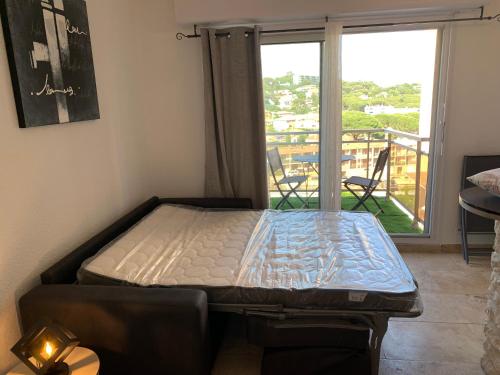 a bed sitting in a room with a balcony at A 10mn de la plage!! in Cavalaire-sur-Mer