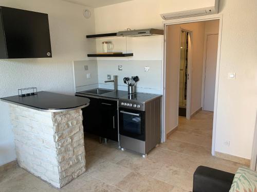 - une cuisine avec un comptoir, un évier et une cuisinière dans l'établissement A 10mn de la plage!!, à Cavalaire-sur-Mer