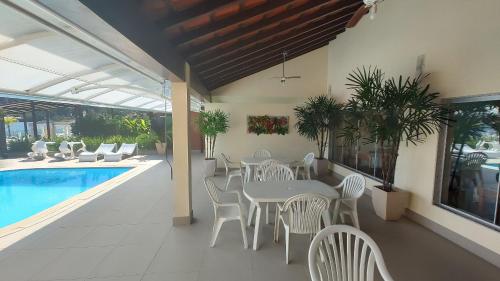 Un patio con mesa y sillas junto a una piscina. en Lindo 3 Qts com Deck churrasqueira Piscina Angra, en Angra dos Reis