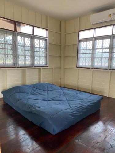 1 dormitorio con 1 cama azul en una habitación con 2 ventanas en Royal mountain field (บ้านทุ่งเขาหลวง ราชบุรี) en Ratchaburi