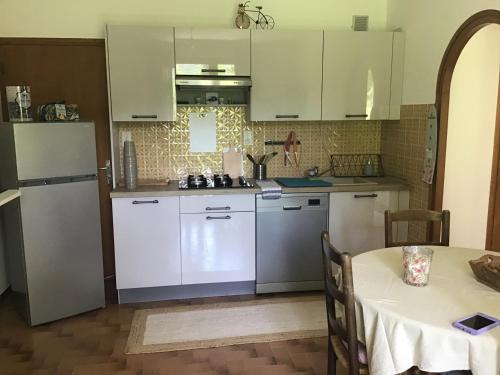 a kitchen with white appliances and a table with a table cloth at Le petit gîte in Saint-Étienne-le-Laus