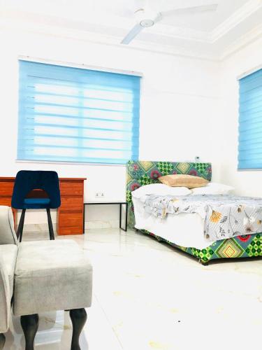 a bedroom with two beds and a chair at Mavern House Apartments in Elmina