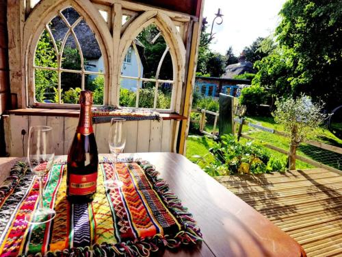 a bottle of wine sitting on a table with glasses at Piddle Puddle Cabin in Dorchester