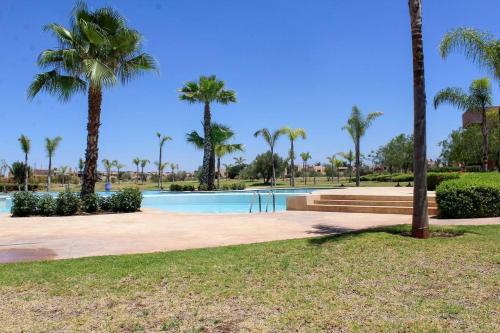 a swimming pool with palm trees in a park at BEL APPART FONCTIONNEL PRESTIGIA GOLF MARRAKECH in Marrakesh