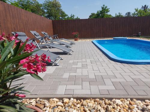 a swimming pool with chairs and flowers next to a fence at Hódvár Apartman in Tiszafüred