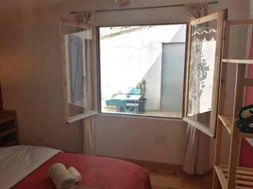 een slaapkamer met een raam met uitzicht op een tafel bij Gîte entre mer et Cévennes in Le Cailar