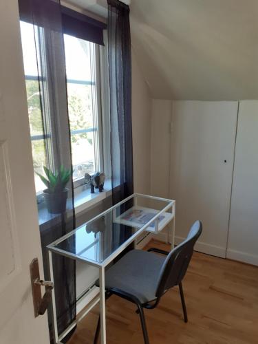 a glass table and a chair in a room with a window at Åberg12 in Höör