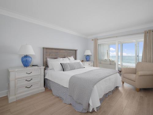 a white bedroom with a bed and a chair at El Mar Villa in Ponte Vedra Beach