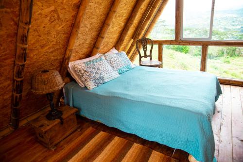 a bed in a room with a large window at Glamping brisa de guadua in Moniquirá