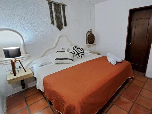 1 dormitorio con 1 cama con colcha de color naranja y blanco en Apartamento Bizantino en Cozumel