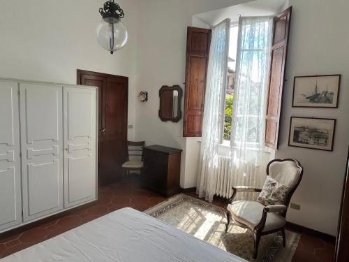 a bedroom with a bed and a chair and a window at Villa Vanna - the ancient Forte just in the center in Forte dei Marmi
