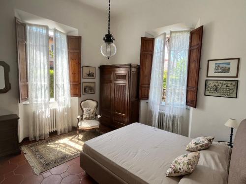 a bedroom with a bed and a chair and windows at Villa Vanna - the ancient Forte just in the center in Forte dei Marmi