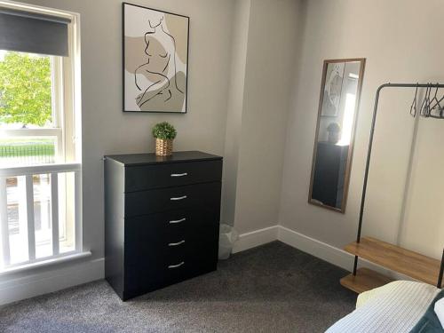 a bedroom with a black dresser and a mirror at Poplar House-2Bedroom house in town centre with free Parking by ShortStays4U in King's Lynn