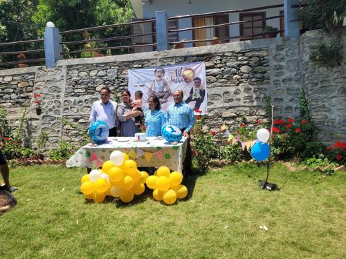 a group of people standing around a table with balloons at Bajoon homestay in Bhīm Tāl