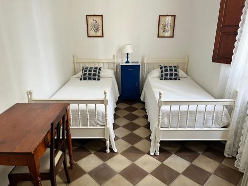 two twin beds in a room with a table and a table at Villa Vanna - the ancient Forte just in the center in Forte dei Marmi
